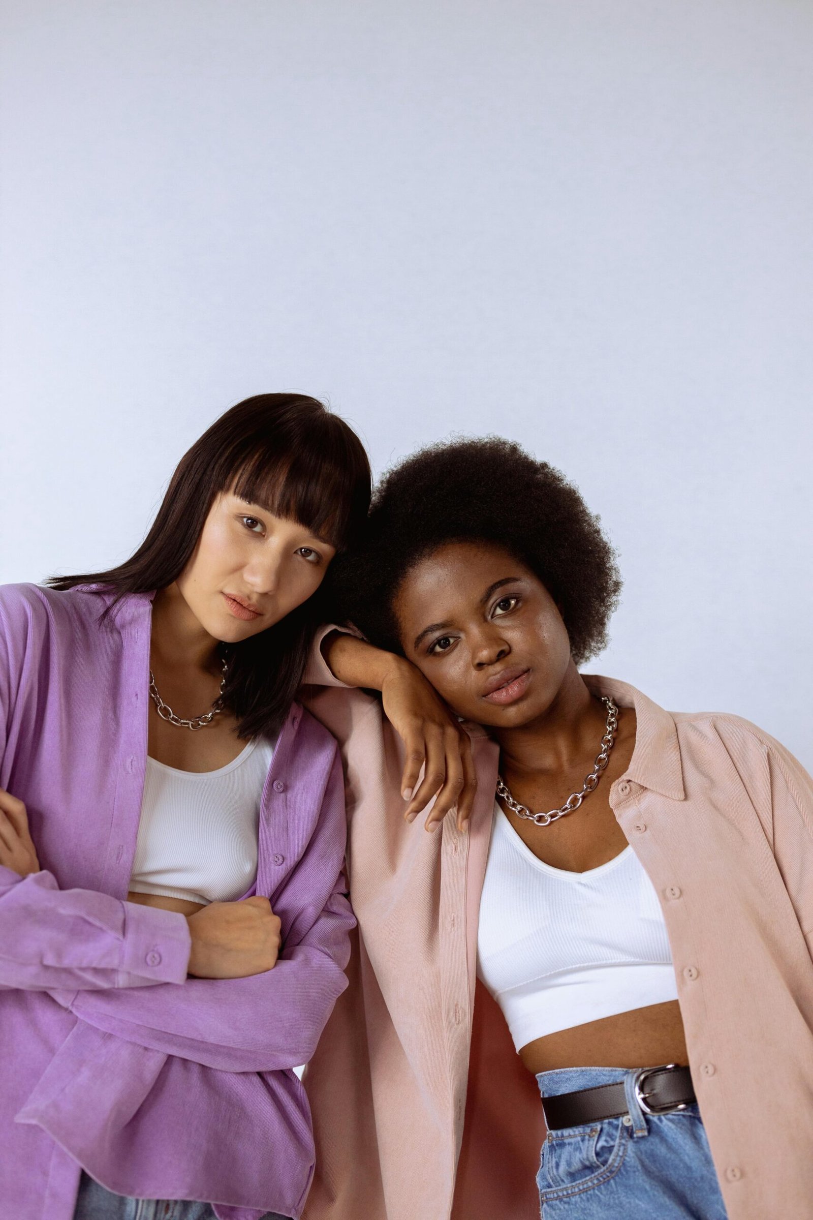 Stylish portraits of two models in a studio with a white background, showcasing modern fashion.