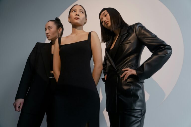 Three fashionable women posing in black clothing during a studio photoshoot.